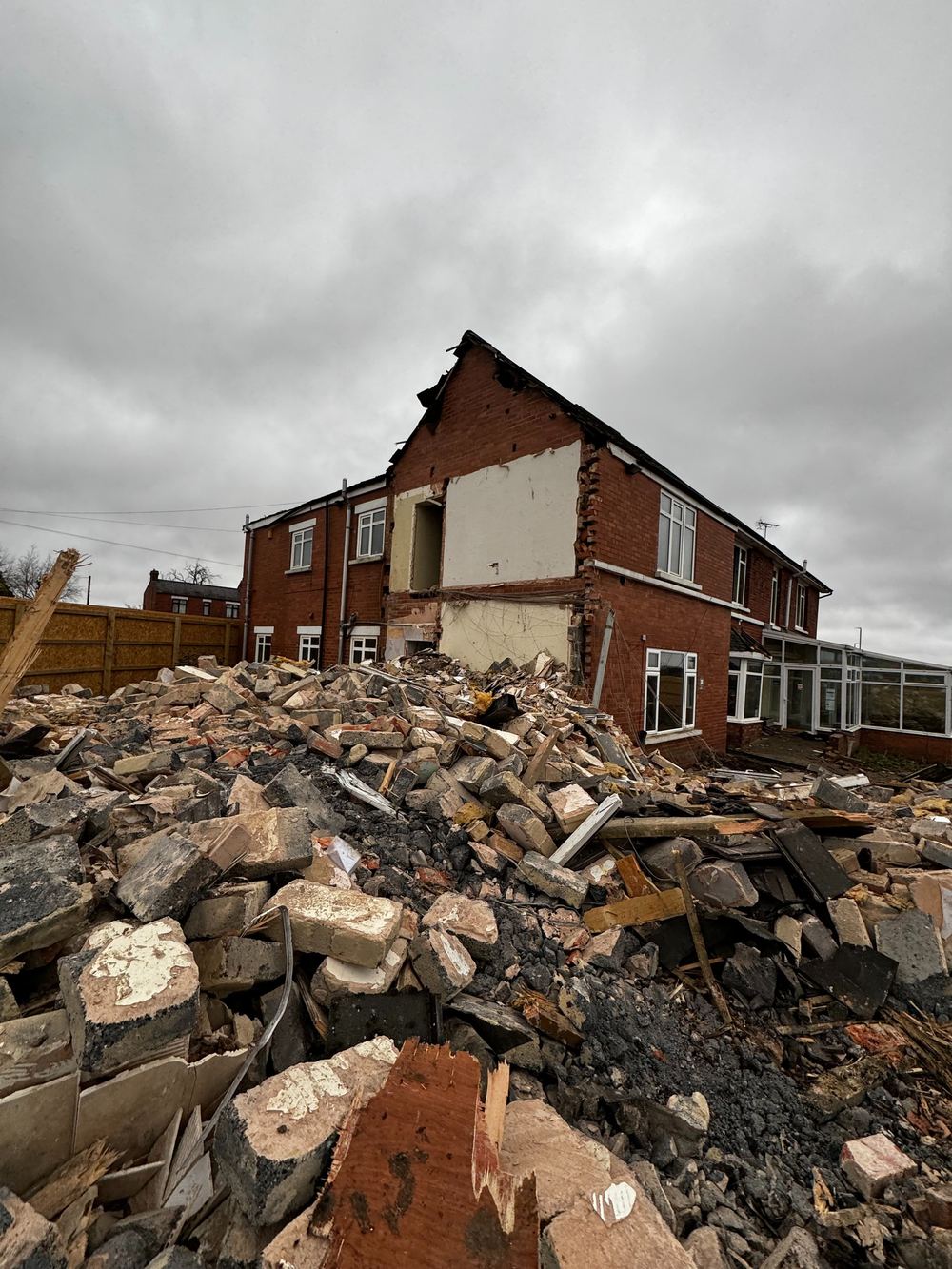 Demolition arisings in front of a part-demolished brick building